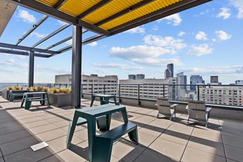 A rooftop patio with a yellow awning and a view of the city skyline.